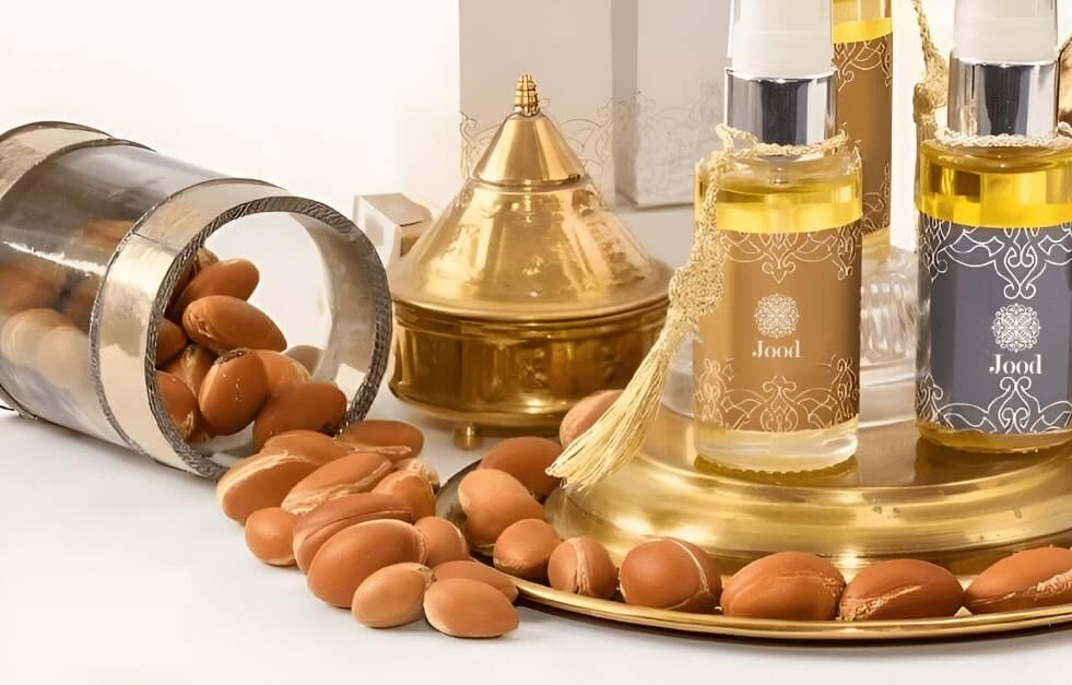 Bottles of argan oil with decorative golden Moroccan elements and scattered argan nuts.