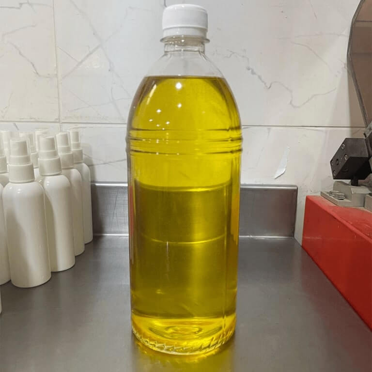 plastic bottle filled with golden yellow oil, placed on a stainless steel